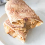 Two stacked peanut butter banana roll-up halves with cinnamon sugar and visible melted chocolate