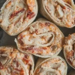 Chicken bacon ranch tortilla pinwheels arranged cut-side up on a dark serving surface