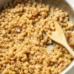 Kid-friendly garlic butter ditalini, lightly coated and served in a shallow metal pan with a wooden spoon.