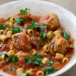 Homemade Spaghetti O’s with small meatballs, ditalini and parsley in a shallow white bowl