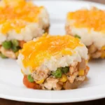 Crustless mini shepherd’s pie cups with visible turkey and vegetables beneath mashed potatoes and melted cheddar