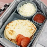 DIY Pizza Lunchables kit with two mini flatbreads, pepperoni, and separate cups of mozzarella and sauce