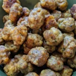 Golden-brown sausage stuffing balls piled in a deep green ceramic bowl