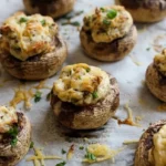 Cream cheese stuffed Baby Bella mushrooms with lightly golden filling and parsley on a parchment-lined baking sheet
