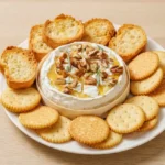 Whole baked Brie with honey, pecans, and rosemary, surrounded by crackers and crostini