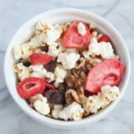 Bowl of healthy popcorn with freeze-dried strawberry slices, walnuts, and dark chocolate chips