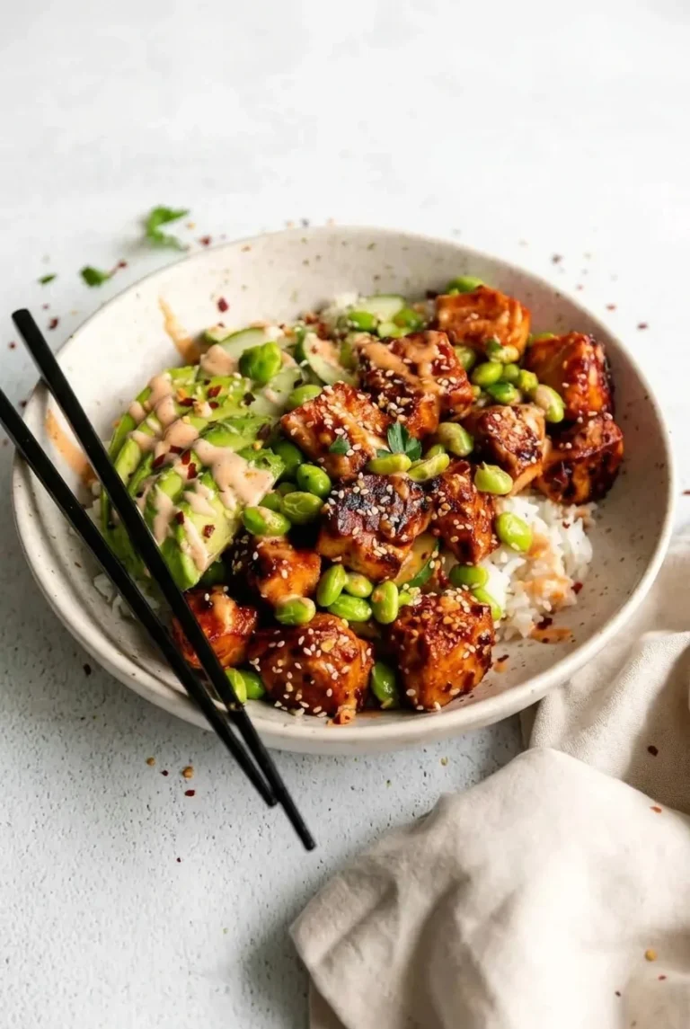 Honey sriracha salmon rice bowl with browned salmon bites, cucumber, avocado, edamame, and creamy drizzle