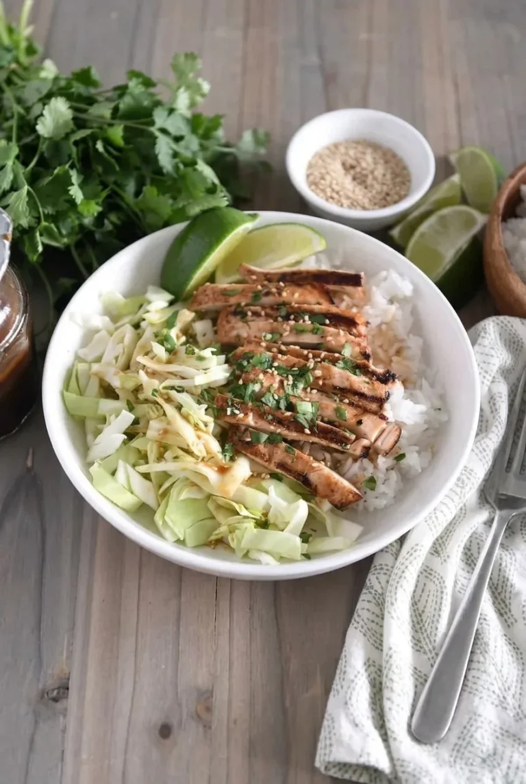 Sticky honey ginger chicken rice bowl with grilled chicken, white rice, chopped cabbage, sesame, cilantro, and lime