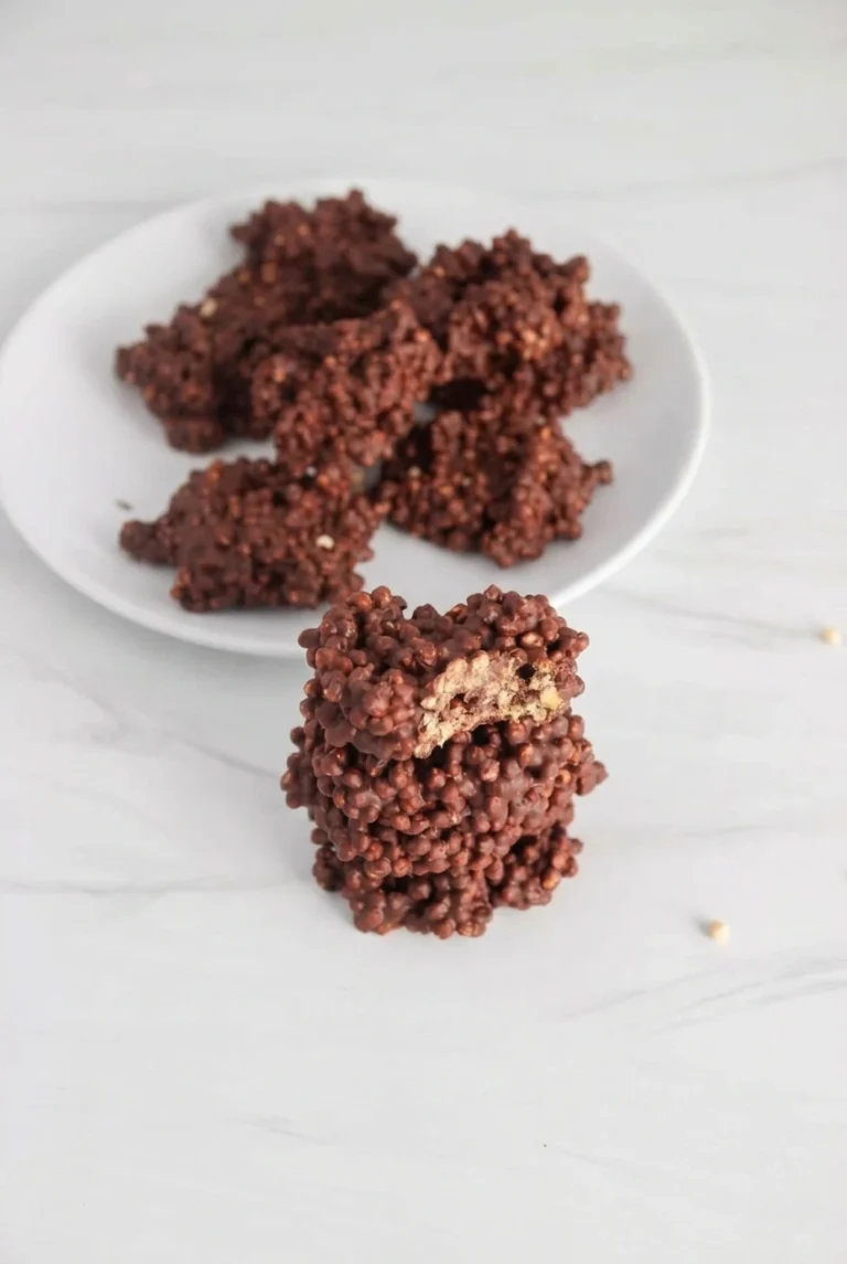 Dark Chocolate Quinoa Crunch Bites Dark chocolate quinoa crunch bites piled on a white plate, with one broken open to show its crisp center.