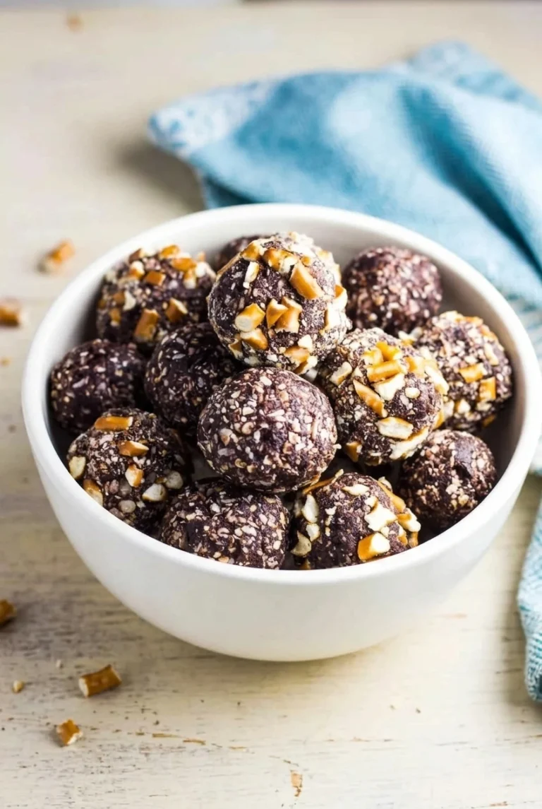No-Bake Date Energy Balls with Cocoa and Pretzels No-Bake Date Energy Balls with cocoa-dark, flecked surfaces and broken pretzel pieces clustered in a white bowl.