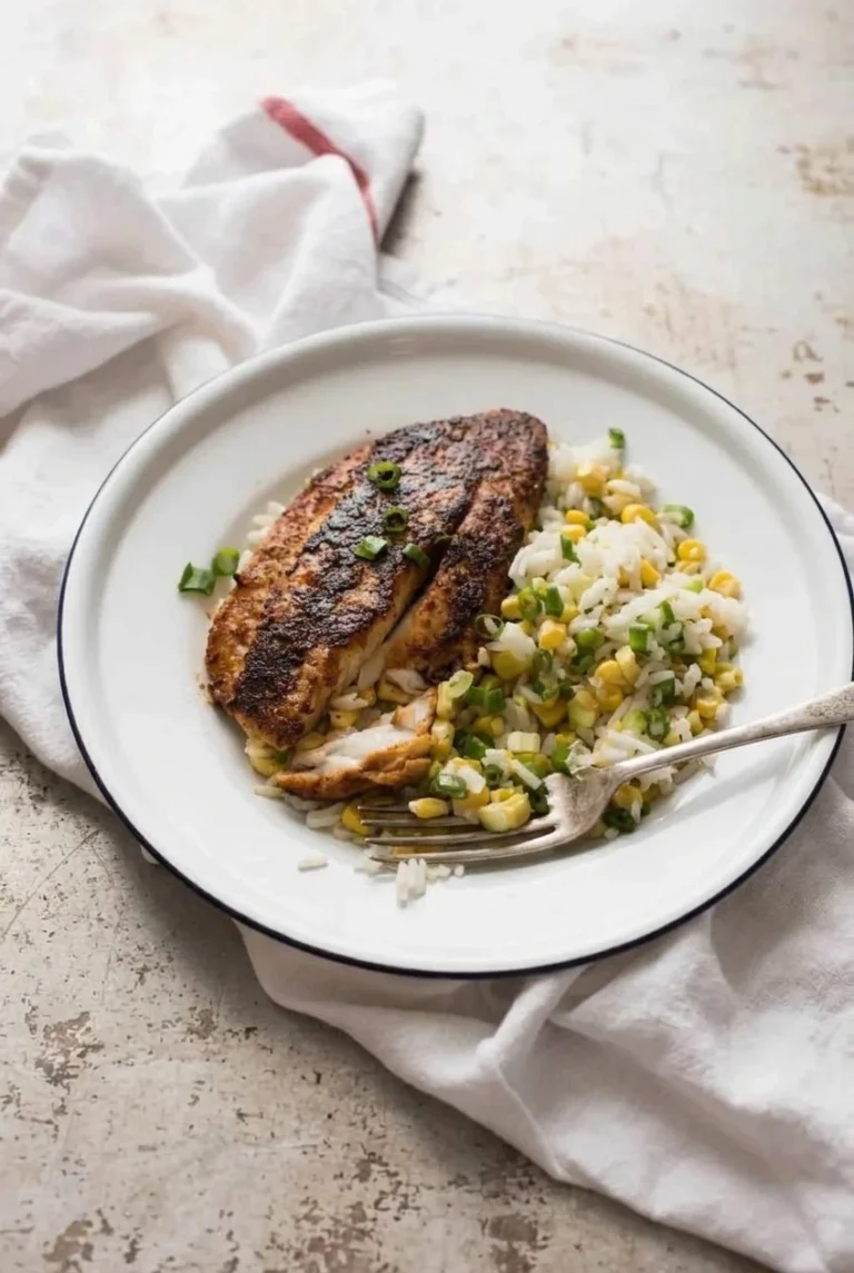 Skillet Blackened Tilapia with Cajun Seasoning Blackened tilapia fillets with flaky white centers, served with rice, corn, and scallions