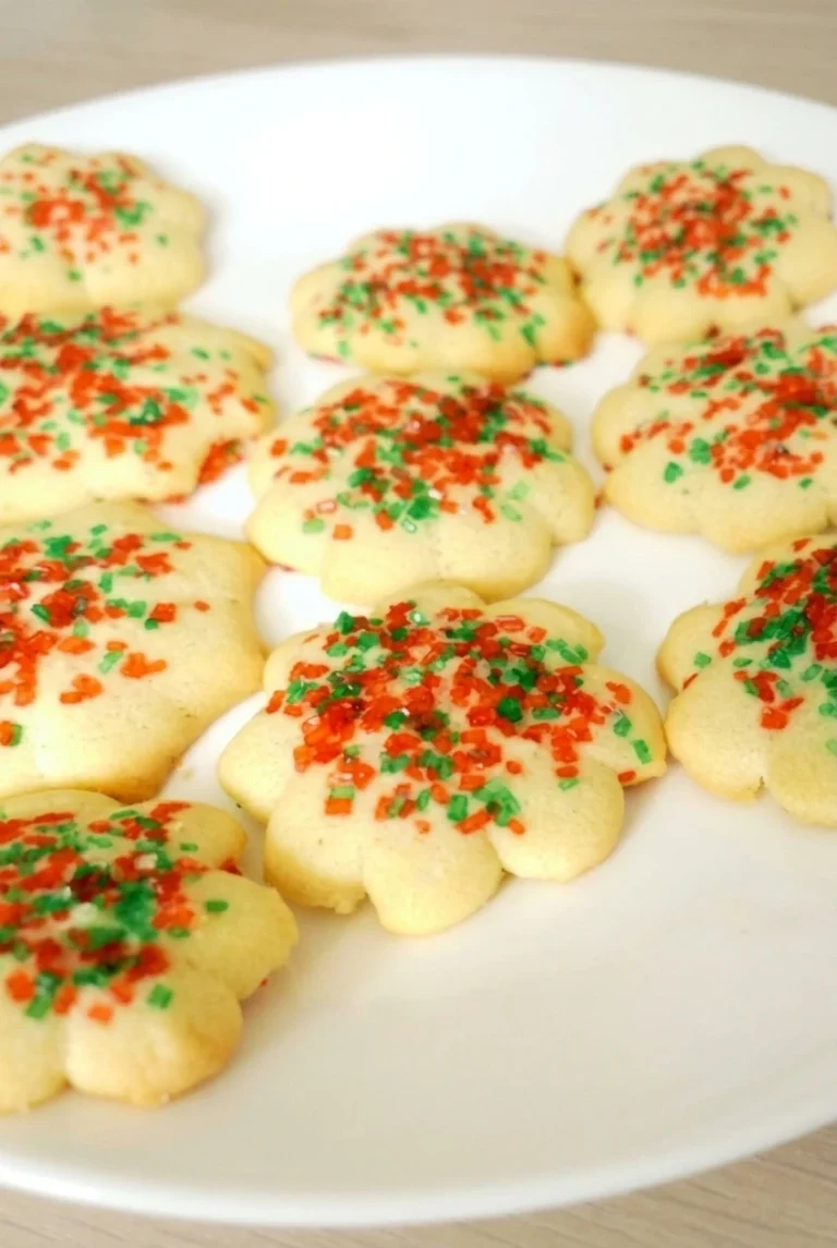 Almond spritz Christmas cookies with red and green sprinkles grouped on a white plate