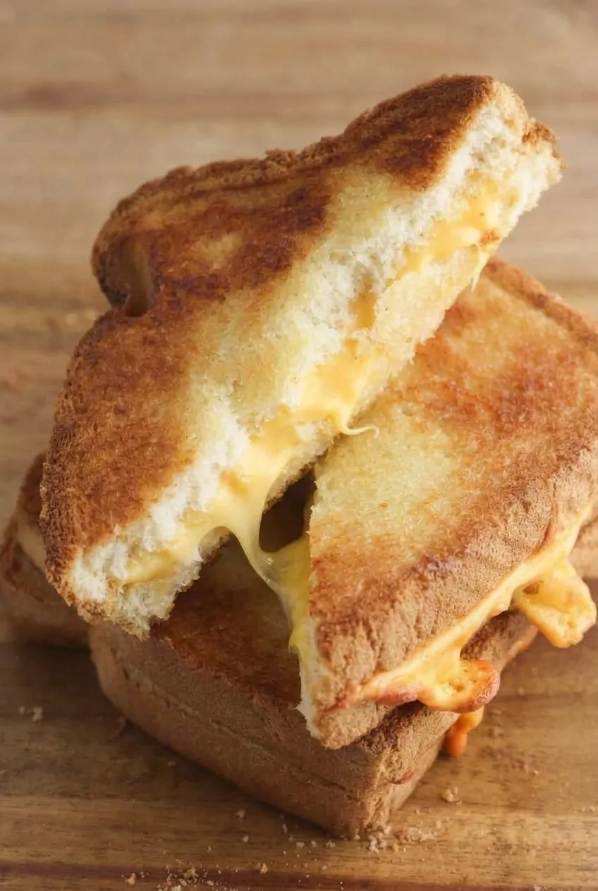 Close view of the grilled cheese cut edge, showing pale bread and melted cheese between golden crusts