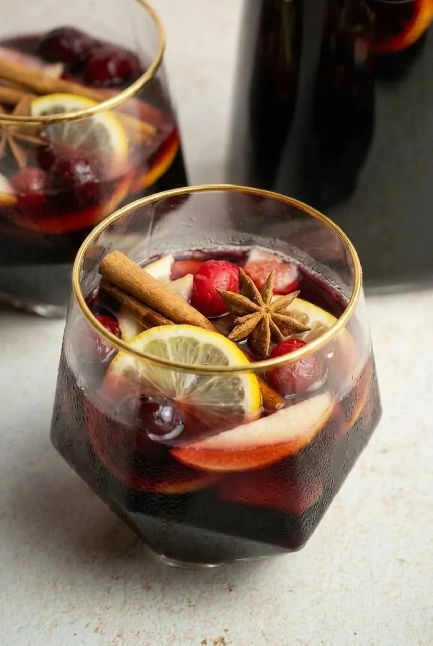 Close view of lemon, apple, cranberries, cinnamon, and star anise in a glass of Thanksgiving sangria