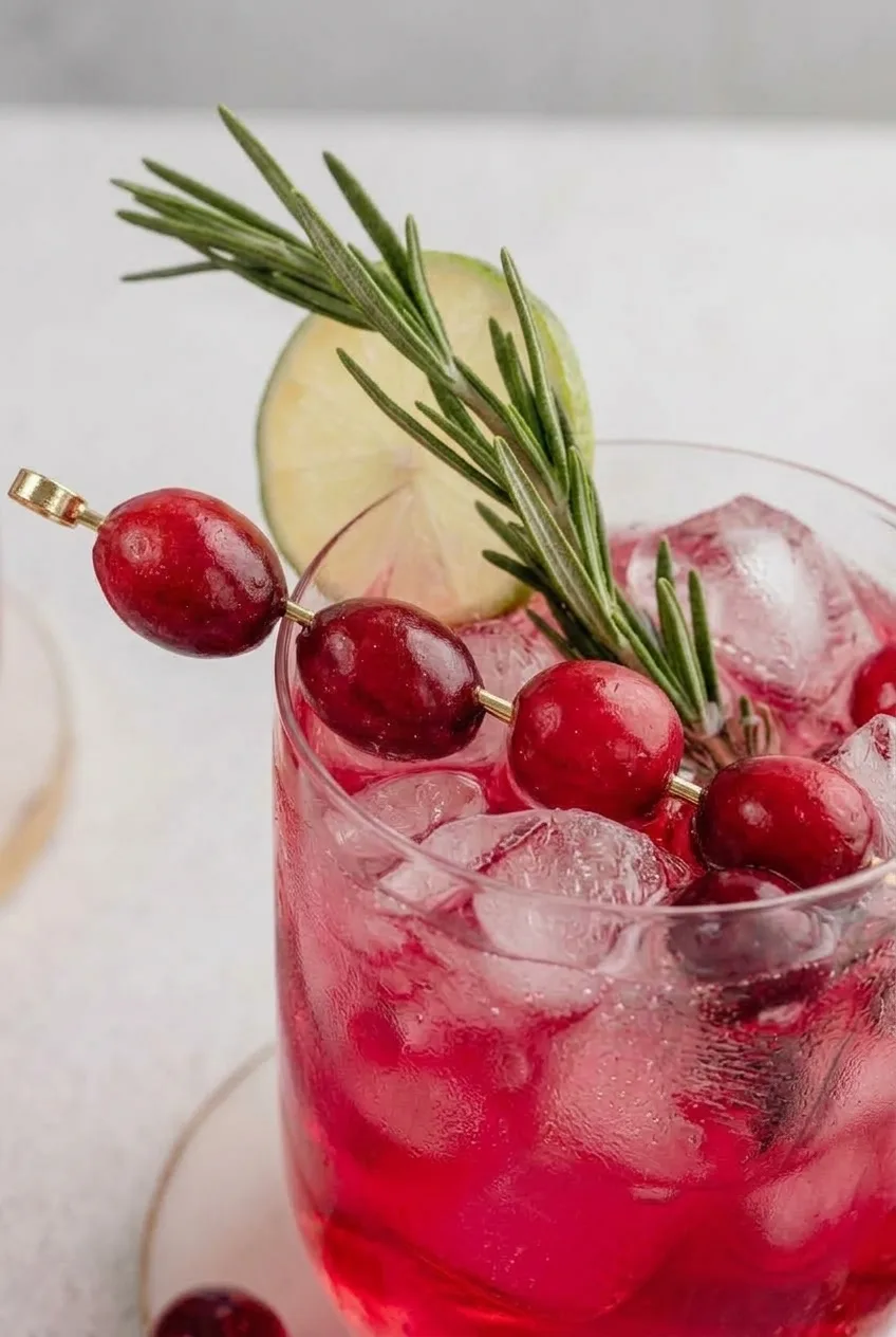 Close view of ice and bubbles beneath the cranberry, rosemary, and lime garnish