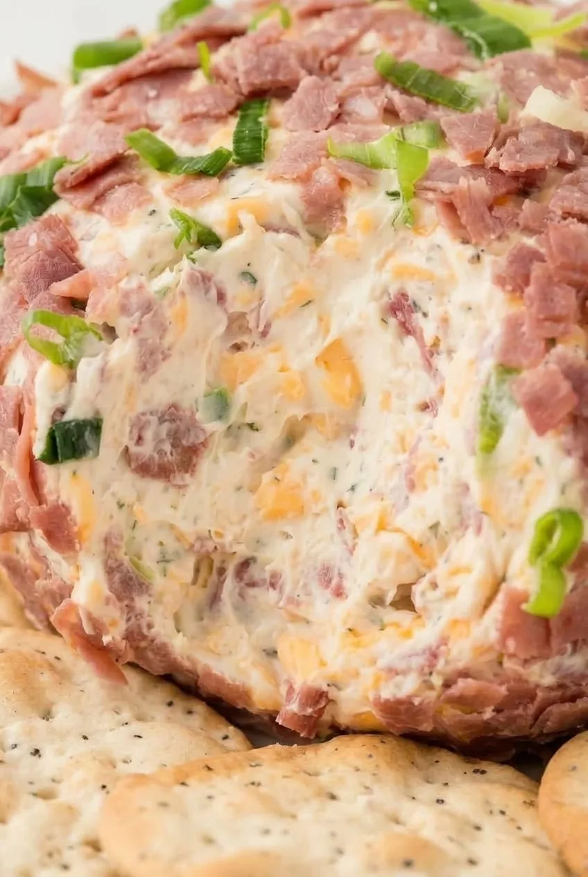 Close view of creamy chipped beef cheese ball filling flecked with cheddar, beef, and green onion