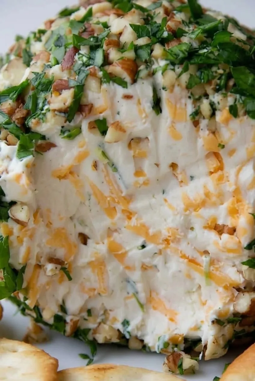Close view of the cheese ball’s creamy cheddar-streaked center and chopped herb-and-pecan coating