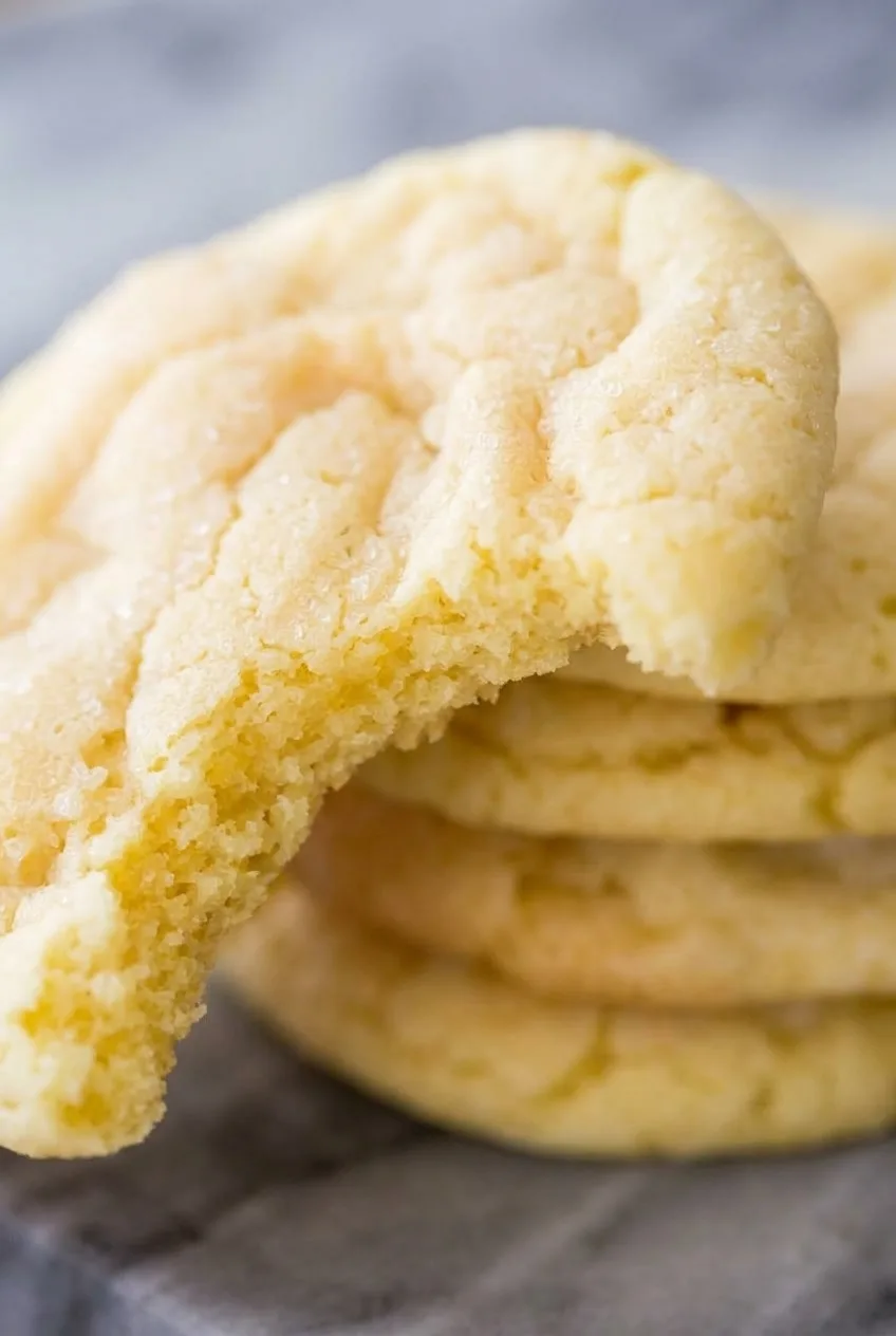 Close view of a broken lemon cookie showing its tender crumb and lightly sugared, cracked surface