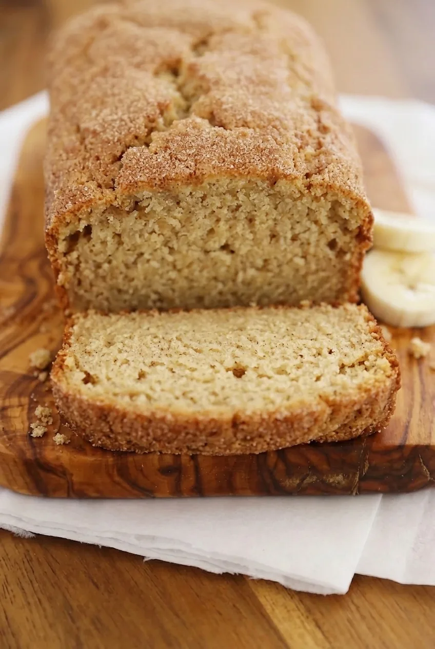 Close view of a banana bread slice showing its soft crumb beneath a cinnamon-sugar crust