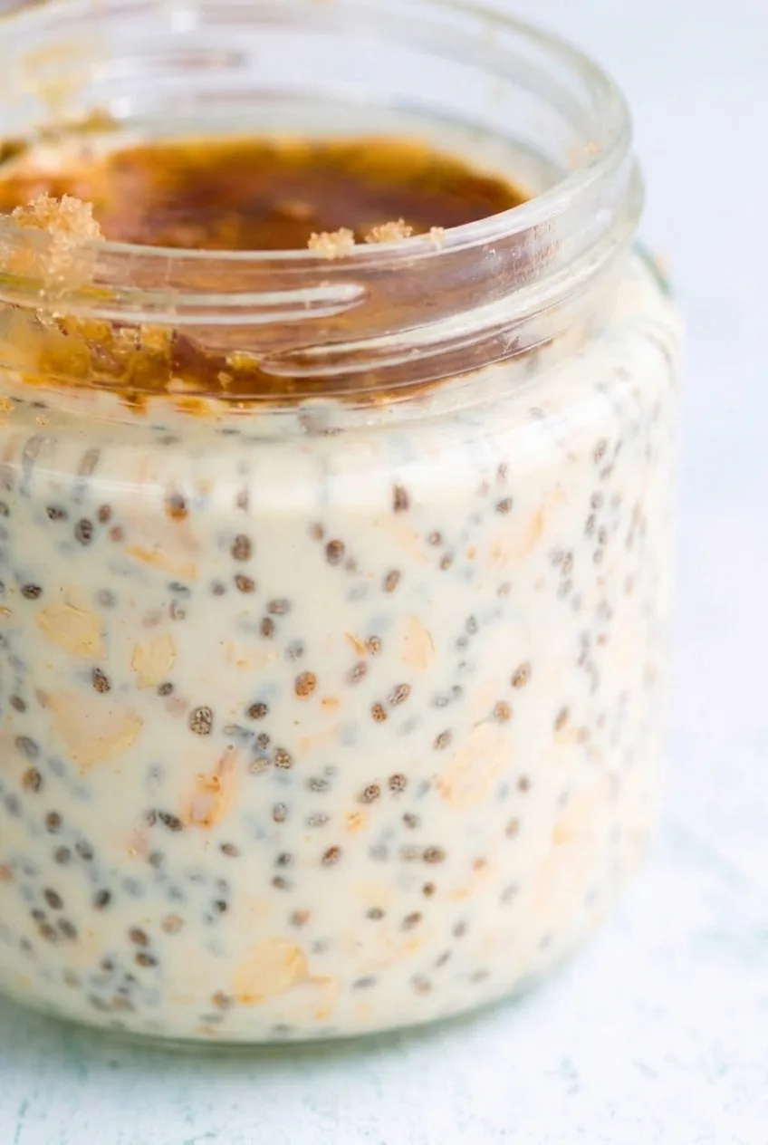 Close view of creamy rolled oats and chia seeds beneath the maple-brown-sugar layer