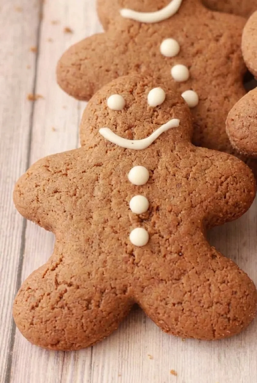 Close detail of a vegan gingerbread cookie's cracked matte surface and raised white icing face and buttons