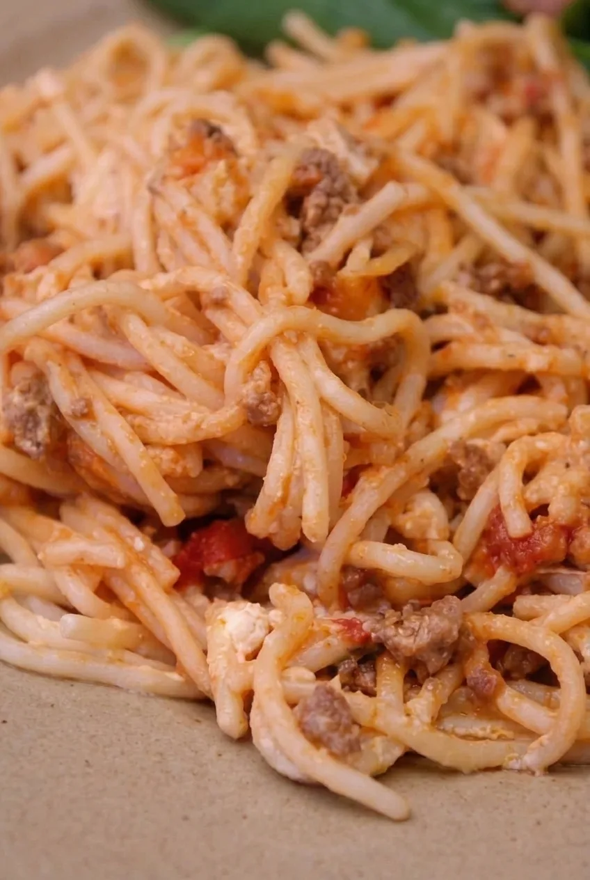 Close detail of Million Dollar Spaghetti showing saucy strands, browned beef crumbles, and creamy cheese
