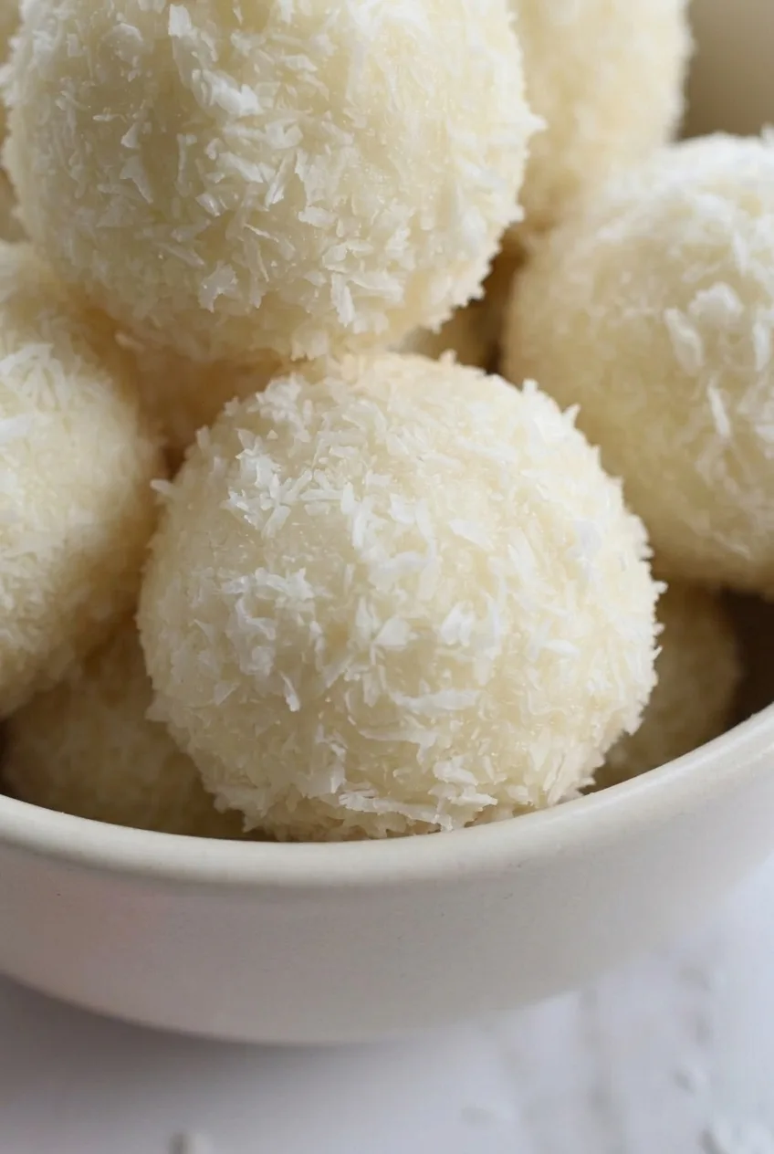 Close view of a coconut truffle's fluffy shredded coating and slightly irregular round shape