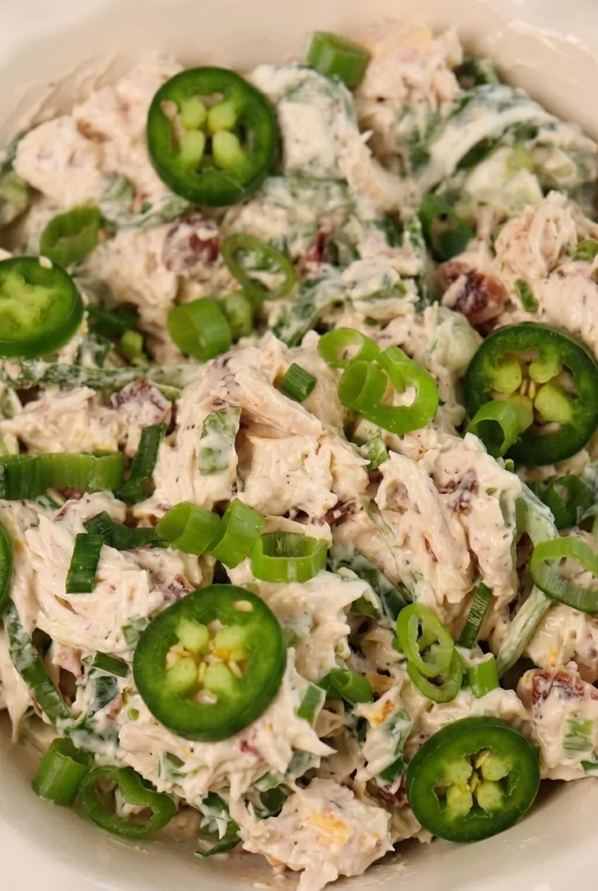 Close detail of creamy jalapeño popper chicken salad showing chicken shreds, bacon, scallions, and pepper