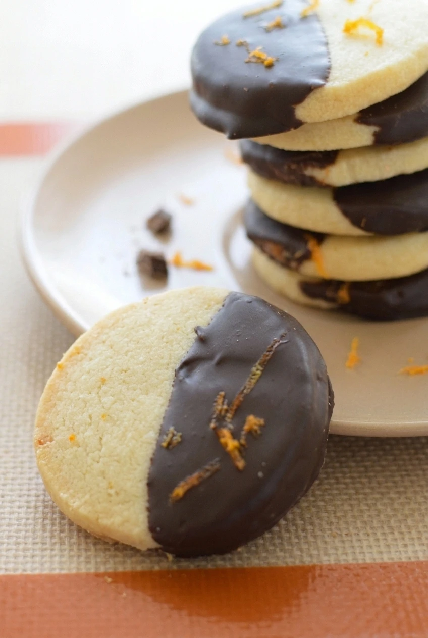 Close detail of chocolate orange shortbread showing its pale crumb, dark chocolate boundary, and fine orange zest.