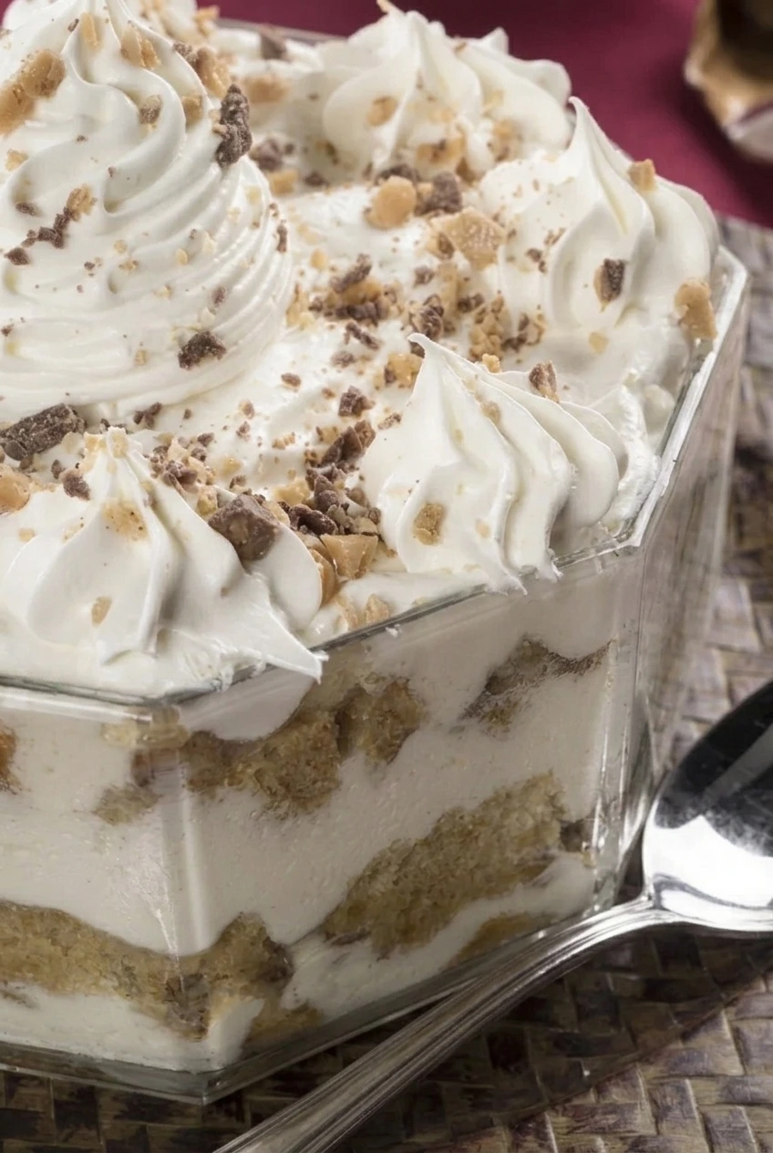 Close view of piped cream, crunchy toffee pieces, and golden cake chunks between mascarpone layers in Christmas tiramisu trifle