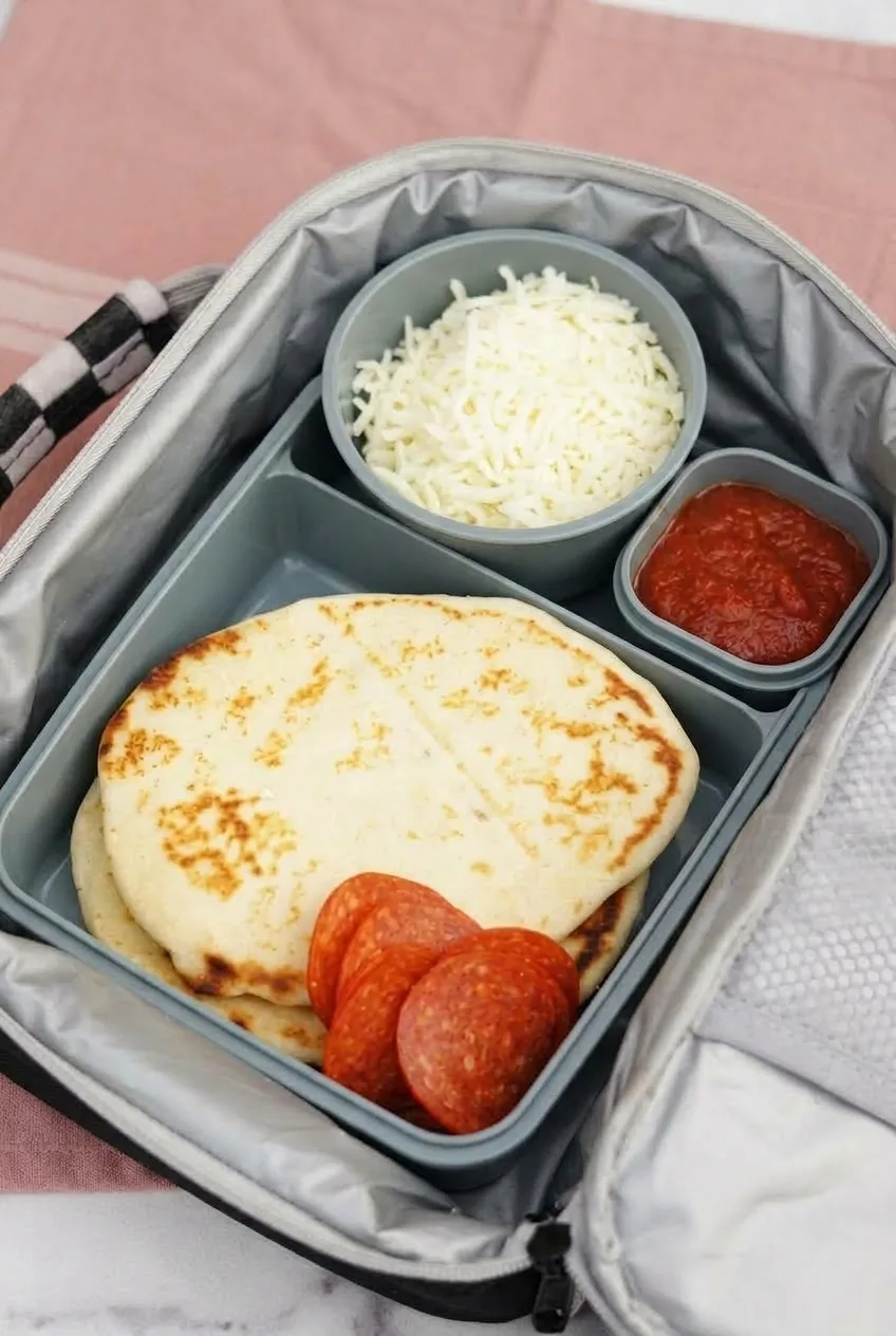Open insulated lunch bag holding a complete DIY Pizza Lunchables kit with toppings packed separately