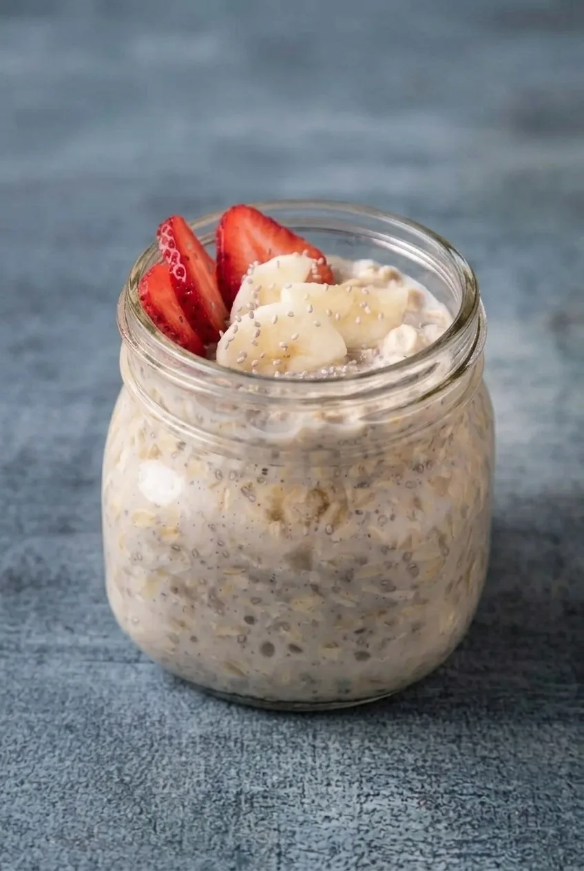 Complete jar of strawberry-banana chia overnight oats on a blue-gray tabletop