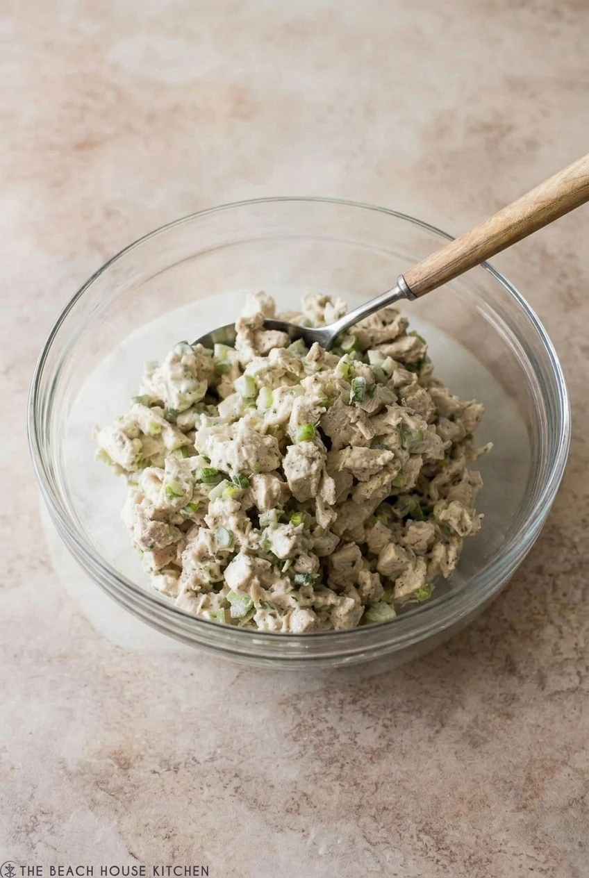 A full bowl of classic creamy chicken salad centered on a light stone surface